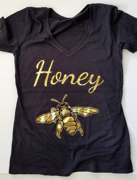 Gold Honey Bee Women's T-shirt. Make a statement and look your best in this fabulous gold foil tee. Soft cotton makes this shirt easy to wear. The bright crisp gold design is the perfect addition to your sunny spring wardrobe.   Limited edition. Wash gentle inside out and hang dry.  Cotton/poly blend, laundered, tearaway label, form fitted. Can size up.