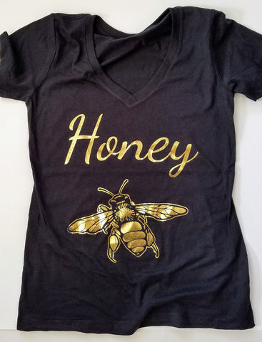 Gold Honey Bee Women's T-shirt. Make a statement and look your best in this fabulous gold foil tee. Soft cotton makes this shirt easy to wear. The bright crisp gold design is the perfect addition to your sunny spring wardrobe.   Limited edition. Wash gentle inside out and hang dry.  Cotton/poly blend, laundered, tearaway label, form fitted. Can size up.