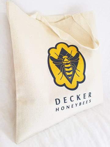 Decker Honeybees Logo Tote. This reusable canvas tote bag is a must have for your everyday life. Use it for groceries, the gym, class or your next festival.   12.0 oz., 100% heavy canvas 20" web canvas handles, 9" drop 15"W x 16"H   Hand wash only/Printed on one side.  Easy on the environment!